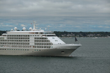 Ultra luxury all inclusive deluxe cruiseship cruise ship yacht liner Whisper or Shadow anchoring in bay in Newport, Rhode Island with New England houses, sailing boats and coastal landscape scenery