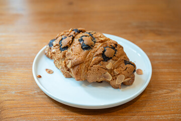 Croissants in white plate on wooden table in coffee shop..