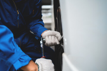 A mechanic is working on a car tire. Concept of focus and determination as the mechanic uses a wrench to loosen the lug nuts. The scene suggests that the mechanic is skilled