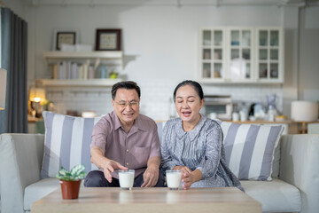 An elderly couple enjoys a peaceful moment at home, sharing smiles and drinks. The warm and cozy atmosphere emphasizes their deep connection, happiness, and the comfort of spending time together.