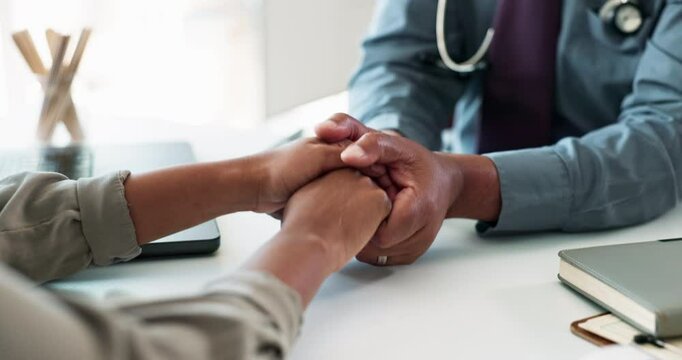 People, doctor and holding hands with patient or empathy on desk for comfort, understanding or breaking news at hospital. Closeup, medical employee and client touch for hope, faith or help at clinic