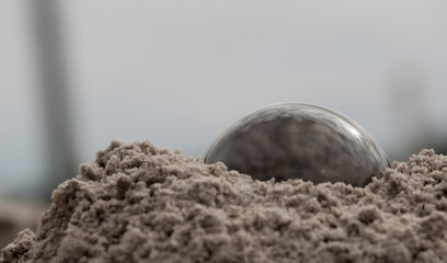 The glass ball is lying in the sand