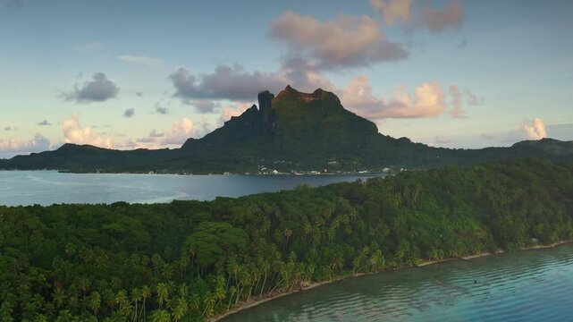 Bora Bora tropical paradise aerial landscape, breathtaking perspective of mount Otemanu, crystal lagoon, palm tree forest under gorgeous pink hues sunset. Explore French Polynesia travel destination