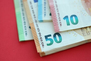 Big amount of one hundred, twenty, ten and fifty euro money bills on red background