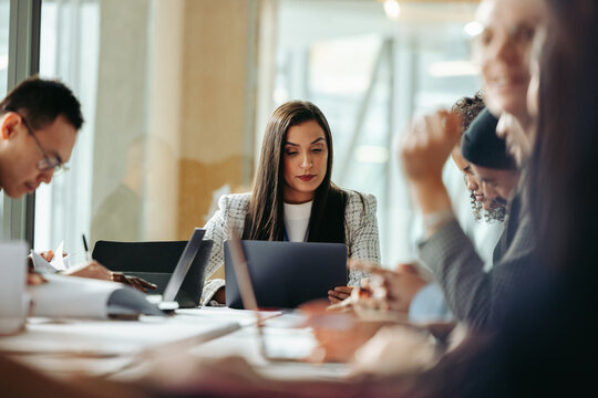 Group of professionals engaging in collaboration during a business meeting in a modern office setting, focusing on teamwork and communication