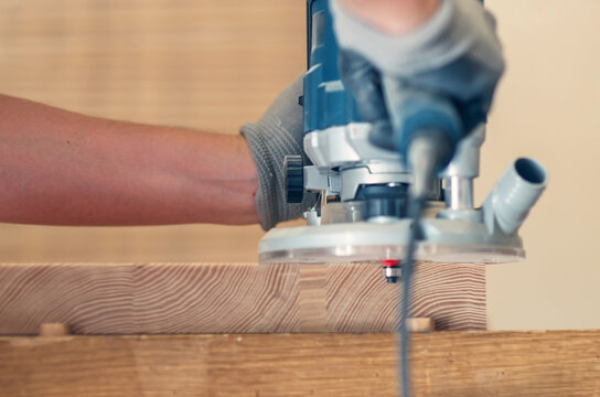 Manual wood router rounding off corners of a wooden plank, detailed woodworking process