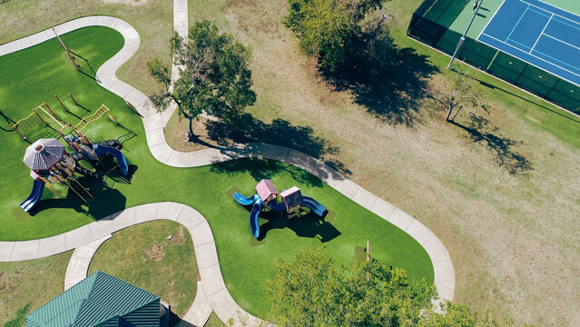 Pavilion, picnic tables and shaded children playground with artificial turf near tennis courts in outdoor recreational facility sport complex in Carrollton, Texas, shaded kids playing structure