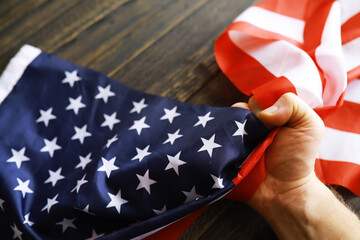 Close-up of Hand Clutching American Flag on Wooden Surface Reflecting Patriotism