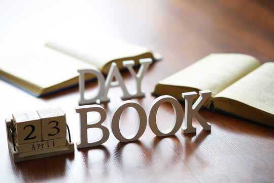 Day Book with Calendar on April 23rd and Open Books on Wooden Table