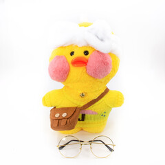 Soft children's toy yellow duck with a handbag and glasses. Isolated object on a white background.