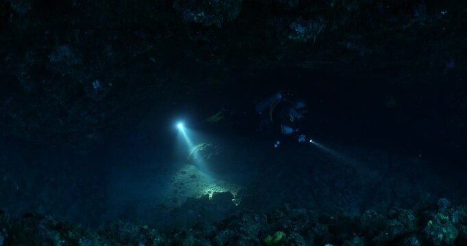 cave diving underwater scuba divers exploring cave dive with torch light in cavern ocean scenery