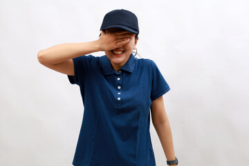 Young hispanic woman wearing delivery uniform and cap smiling and laughing with hand on face covering eyes for surprise. blind concept.