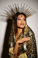 An alluring goddess adorned in a golden dress showcases her beauty with grace in an artistic studio...