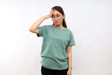 Bothered and tired asian woman, looking complicated, touching forehead, face palm sign, looking distressed at camera, white background