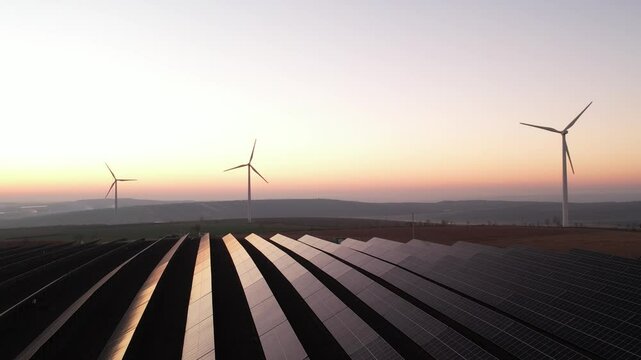 Solar panels park and wind turbines at sunset.Windmill turbines generating green energy electric.Green energy reduce carbon emissions and makes earth cleaner and more ecological.	
