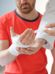 doctor bandaging the hand of a sport man after an accident