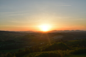 The sunset and its rays dazzle the green forests and meadows