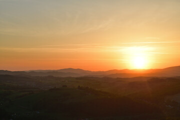 The sunset and its rays dazzle the green forests and meadows