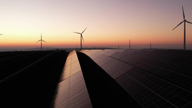 Solar panels park and wind turbines at sunset.Windmill turbines generating green energy electric.Green energy reduce carbon emissions and makes earth cleaner and more ecological.	
