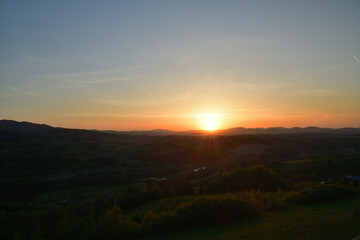 The sunset and its rays dazzle the green forests and meadows