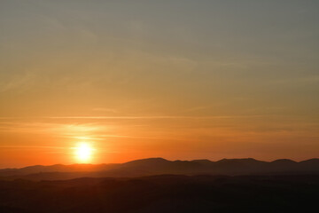 The sunset and its rays dazzle the green forests and meadows