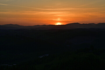 The sunset and its rays dazzle the green forests and meadows