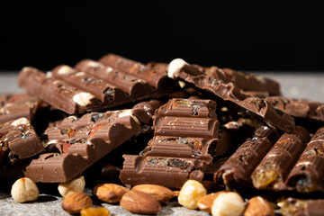 Lots of chocolate bars with nuts and raisins on a black background