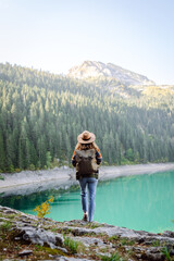 Female traveler enjoying the view of Lake among mountains. Hiking with backpack. Active lifestyle.