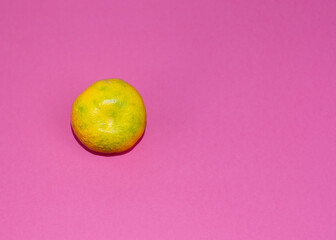 Single mandarin on pink background