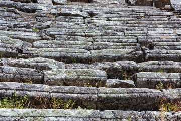 Close-up of ancient stone seating in the ruins of the theater at Sagalassos, showing weathered, moss-covered stones with plant growth. Aglasun, Burdur, Turkey (Turkiye)
