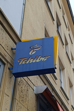 Schild mit dem Tchibo Logo an einer Hauswand &uuml;ber dem Laden