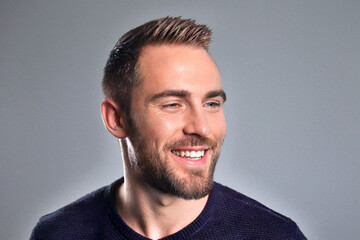 Fototapeta premium Smiling Man with Beard in Casual Attire Against a Neutral Background