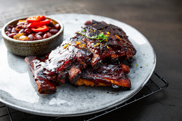 Roasted Pork Ribs in BBQ Sauce with Red Beans in the plate close up