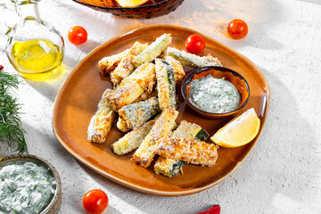 Healthy zucchini fries with yogurt and herbs sauce on white background