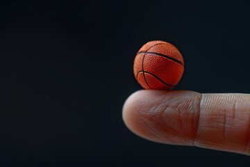 A miniature basketball balancing on the tip of a finger against a dark background, showcasing precision and focus in a playful moment