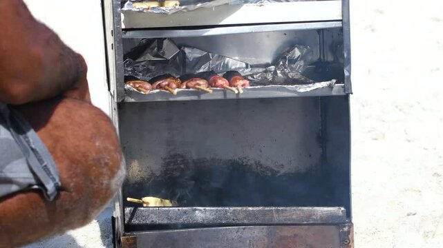 Man preparing grilled curd cheese and some meats on a portable barbecue. Typical food sold on the beaches of Brazil.