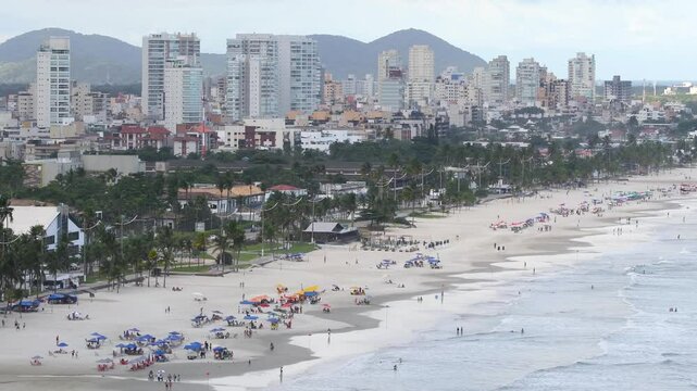 Aerial view of Enseada Beach, a beautiful beach with a view of the shore, of the sea, Guaruja city, and some hills in the background. Guaruja - SP, Brazil. Time lapse video.