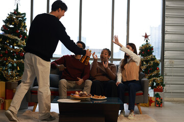 Happy group of friends cheering  and drinking beer  and making a toast during  Christmas celebration in the living room at home 