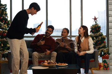 Happy group of friends cheering  and drinking beer  and making a toast during  Christmas celebration in the living room at home 