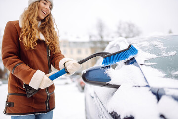 Woman cleaning snow from car windshield. Scraping ice. Transport, winter, weather, people and...