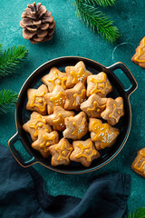  Festive Christmas cookies decorated with golden icing in a black plate. Dark blue background top view vertical photo
