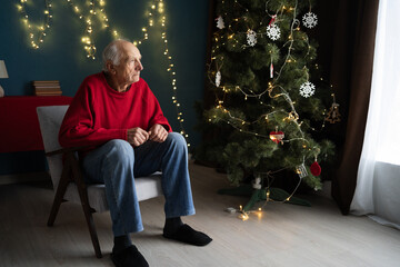 lonely pensioner sitting on a chair in the living room at Christmas expecting children.