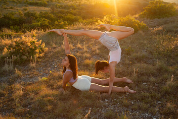 Fly yoga. Women gymnasts practicing in the bright rays of the sunset