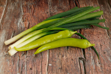 fresh green onions with peppers on rustic wood
