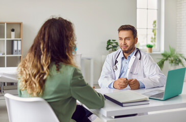Portrait of a young woman patient in office listening to recommendations of friendly male doctor...