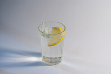 Refreshing water in a low glass with ice cubes and a slice of lemon.