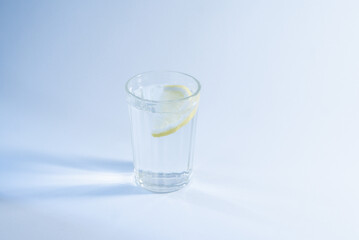 Refreshing water in a low glass with ice cubes and a slice of lemon.