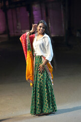 A radiant smile and colorful traditional dress light up the night cityscape. A beautiful blend of culture and modern city glow.