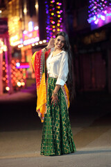 A radiant smile and colorful traditional dress light up the night cityscape. A beautiful blend of culture and modern city glow.
