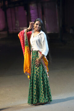 A radiant smile and colorful traditional dress light up the night cityscape. A beautiful blend of culture and modern city glow.